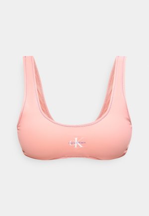 Gaiši rozā Calvin Klein sporta krūšturis ar noapaļotu izgriezumu un redzamu zigzaga šuvi gar malām.