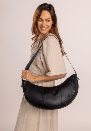 Borsa a spalla in pelle nera con una forma curva e arrotondata, caratterizzata da una superficie liscia e un design semplice. Cinghia lunga per indossarla a tracolla.