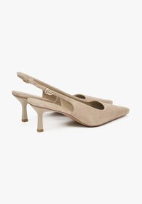 Beige suède slingback schoenen met een puntige neus, een middenhoge hak, uitsparingen aan de zijkanten en een gesp om de sling strap.