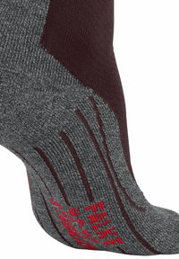 Graue Socke mit kastanienbraunen Akzenten, die strukturierte Muster und rote Branding-Elemente aufweist. Das Design enthält einen gepolsterten Bereich für zusätzlichen Komfort und Grip.