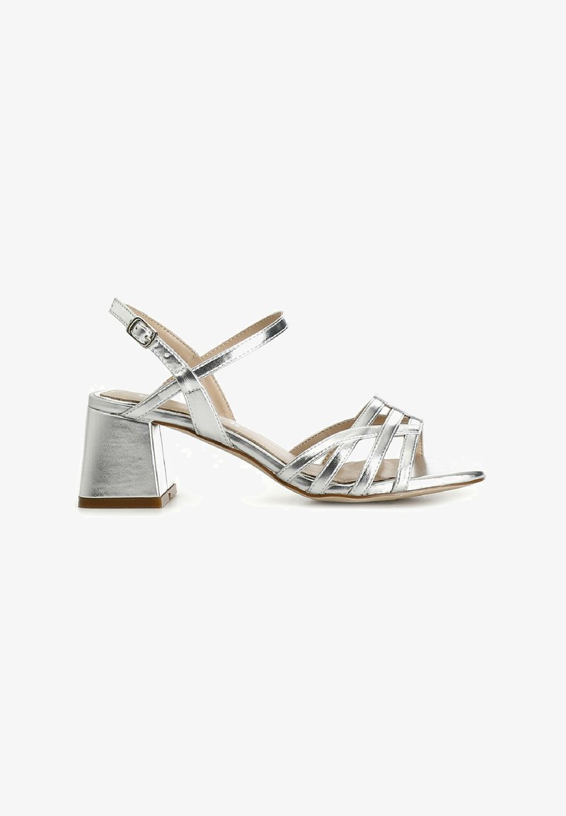 Silver metallic heeled sandals with cross-over straps, open toe design, block heel, and an adjustable ankle buckle. Smooth texture.