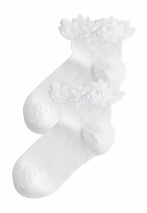 Weiße Knöchelsocken mit einem frillierten Rand, verziert mit kleinen, übereinanderliegenden Blumenapplikationen. Hergestellt aus weichem, dehnbarem Material für zusätzlichen Komfort.