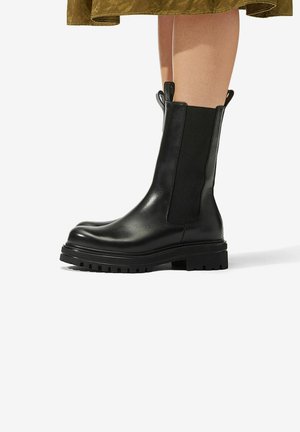 Sorte ankelstøvler lavet af læder, med en glat overflade, elastiske sidepaneler, kraftig sål og trækflapper for nem påtagning.