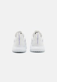 Baskets de sport blanches avec des dessus texturés, des cols rembourrés et des accents violets. Semelles à rainures pour une meilleure adhérence. Marquage sur les talons et les côtés.