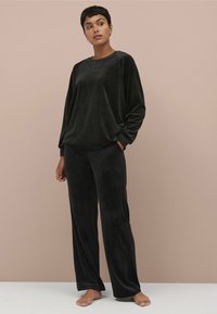 Sorte velour loungewear sæt med en løs pasform langærmet bluse og brede bukser. Blød tekstur med minimale sømme, designet til komfort.