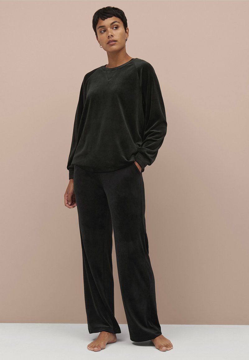 Sorte velour loungewear sæt med en løs pasform langærmet bluse og brede bukser. Blød tekstur med minimale sømme, designet til komfort.