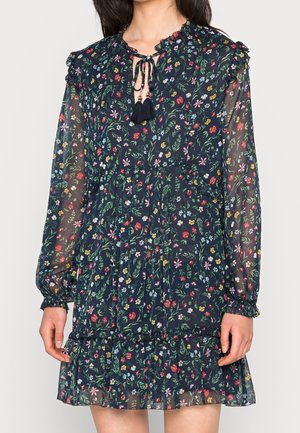 Granatowa sukienka w kwiaty z długimi prześwitującymi rękawami, elastycznymi mankietami, falbanianym dołem i wiązaniem przy dekolcie zakończonym frędzlami.