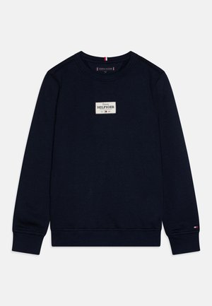 Mörkblå sweatshirt med rund halsringning, strukturerat tyg, en vit rektangulär lapp med "Tommy HILFIGER" och små logotypdetaljer på ärmarna.