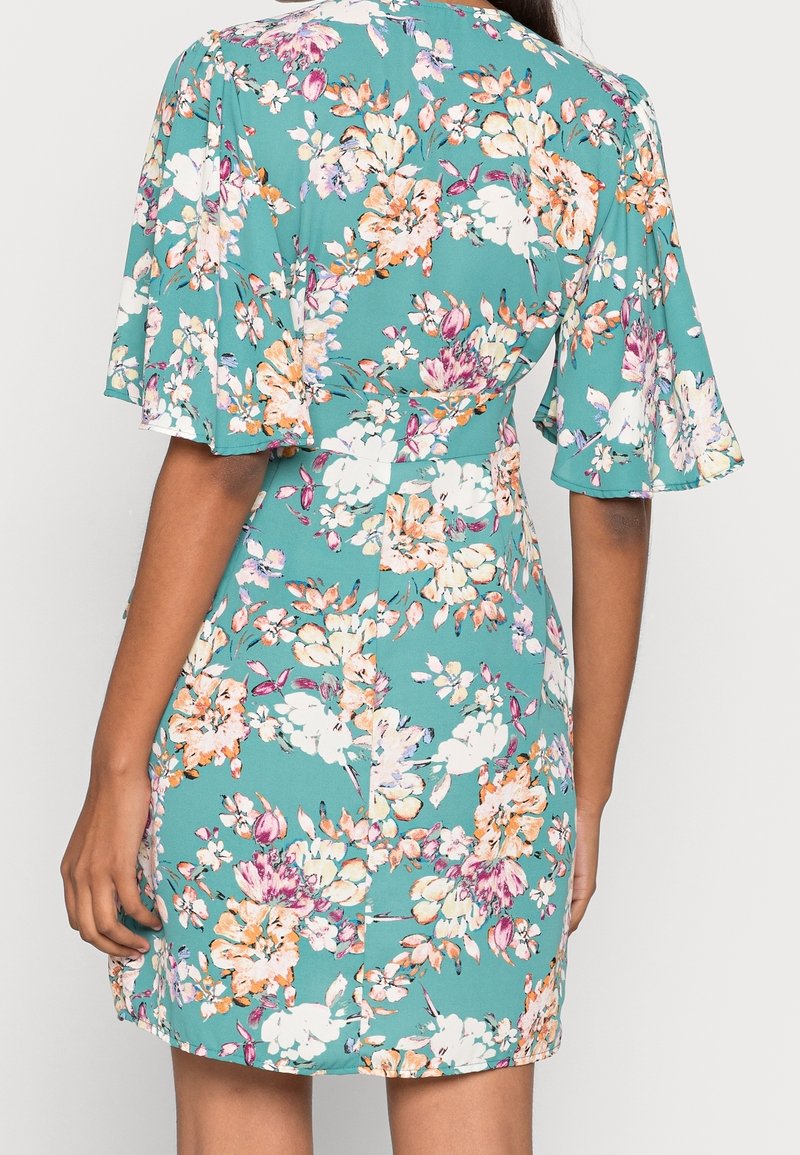 Vestido floral con fondo verde azulado y flores rosas, blancas y naranjas. Mangas cortas acampanadas y cintura ajustada con dobladillo recto.