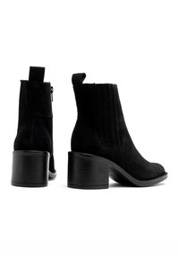 Czarne zamszowe botki za kostkę z okrągłym noskiem, elastycznymi bocznymi panelami i niskim obcasem. Posiadają pętelkę ułatwiającą zakładanie.