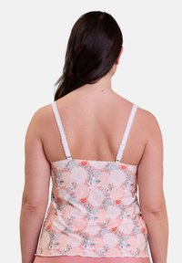 Camisole floral en rose pastel avec des liserés en dentelle blanche et des bretelles ajustables. Présente un motif floral en gris et orange sur un fond doux.