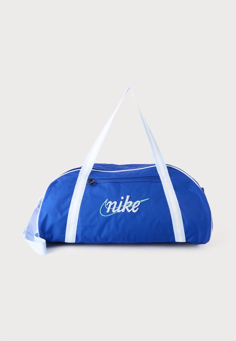 Μπλε τσάντα Nike duffel με λευκές λουρίδες και μπροστινή τσέπη με φερμουάρ σε απλό ανοιχτό φόντο.