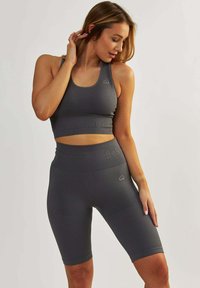 Szary zestaw sportowy składający się z dopasowanego topu na ramiączkach i szortów z wysokim stanem, z prążkowaną teksturą, subtelnym logo i akcentami w kształcie serca.