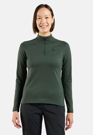 Donkergroene sportshirt met lange mouwen, hoge kraag, half-rits sluiting en logo op de borst. Glad, vochtafvoerend materiaal.