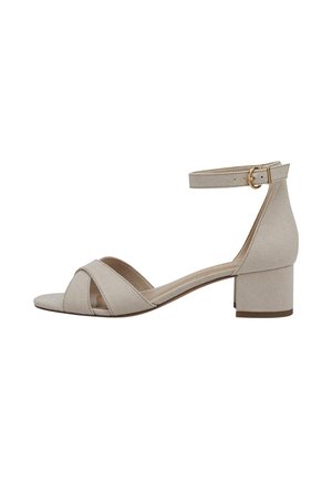 Sandal in suede beige con cinturino alla caviglia, fasce incrociate sulle dita e un piccolo tacco a blocco. Dettaglio della fibbia in tono oro sul cinturino.