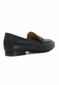 Zwarte leren loafer met een platte zool, ronde neus en subtiele gouden hardware accenten. Gladde textuur met gestikt details langs de randen.