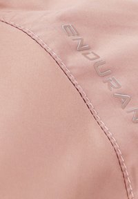 Rosa tyg med en slät textur och synliga sömmar. Silverfärgad "ENDUR"-logotyp tryckt på ytan, vilket visar modern design och detalj.