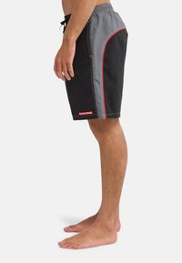 Μαύρα και γκρι βερμούδα με κόκκινες λεπτομέρειες, με κορδόνι στη μέση και πλαϊνές τσέπες στη ραφή, με λεία υφή και αθλητικό σχέδιο.