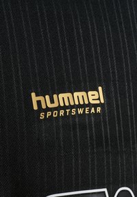 Czarna tkanina o strukturze z złotym logo „hummel” i nadrukiem "SPORTSWEAR".