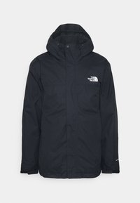 Czarna wodoodporna kurtka z wysokim kołnierzem i kapturem, zapinana na zamek z przodu, z logo na lewej piersi. Gładka struktura, lekka konstrukcja.