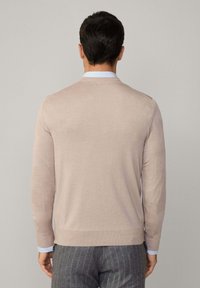 Svetlo béžový pletený sveter s okrúhlym výstrihom, dlhými rukávmi a rebrovaným lemom. Nosí sa na svetlomodrej košeli s golierom.