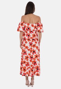 Abito maxi floreale con maniche a sbuffo, caratterizzato da fiori rossi e pink su sfondo bianco, design a strati e scollo off-the-shoulder.