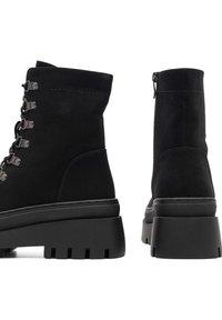 Čierne členkové topánky z semišu s robustnou platformou a gumovou podrážkou, s kovovými očkami a bočným zipsom pre ľahký prístup.