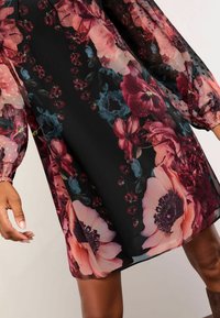 Rochie florală cu un fundal negru, flori mari roz și roșii, mâneci pufoase transparente și o siluetă lejeră, dintr-un material texturat.