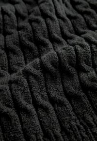 Tissu noir texturé avec un motif en relief ; surface douce et moelleuse ; met en valeur la profondeur et la dimension dans le design tissé.