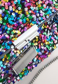 Daugiaspalvė blizgučių rankinė su chromuota užsegimo detalė ir tekstūruota juodos audinio pagrindu. Matomas grandinėlės dirželis ir metaliniai akcentai.
