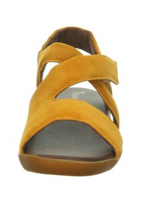 Gelbe Wildledersandale mit überkreuzten Riemen, offener Zehenpartie und flacher Gummisohle. Das Innenfutter verfügt über eine dunkelgraue, strukturierte Fußbett.