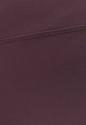 Close-up van een donkerpaarse stof met een horizontale naad in bijpassende draad gestikt over het midden.