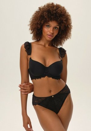 Schwarzes Spitzen-Bralette mit gerafften Trägern und einem glatten Cup-Design. Passende schwarze Spitzenunterhose mit goldenen Akzenten und halbtransparenten Details.