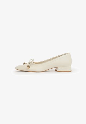 Scarpa da donna color avorio chiaro con tacco basso, punta appuntita, piccolo tacco a blocco e fiocco decorativo con charm dorati sulla parte superiore.