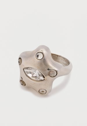 Zilveren metalen ring met een stervorm, voorzien van een heldere marquise geslepen steen en cirkelvormige zilveren accenten rond de band. Glad oppervlak.