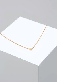 Halskette aus Gold mit einem kleinen Herzanhänger. Die Kette hat ein zartes, strukturiertes Design und eine glänzende Oberfläche.