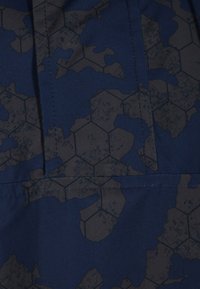 Material naval cu un model de camuflaj hexagonal în gri închis. Prezintă cusături contrastante și o textură netedă și durabilă.