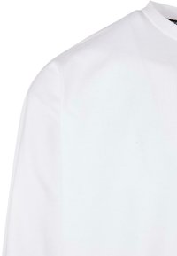 Chemise blanche à manches longues avec un col rond. Dotée d'une texture lisse et douce, elle offre une coupe décontractée. Design simple, sans motifs ni accents visibles.