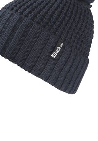 Knitted navy beanie with a textured pattern and a ribbed cuff. Features a small branded label on the side and a pom-pom on top.