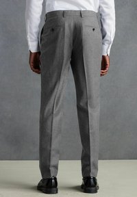 Pantalones de lana grises con corte recto, que cuentan con una textura suave, dos bolsillos traseros y un sutil detalle en las costuras. Se ven zapatos negros.
