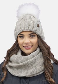 Lichtgrijze gebreide beanie met een witte faux fur pompon bovenop, gecombineerd met een bijpassende textuursjaal. Beide items hebben een zachte stof.