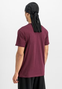 Bordeaux kortærmet T-shirt lavet af bomuld, med rund hals og en afslappet pasform, parret med et sort silke durag bundet bagpå.