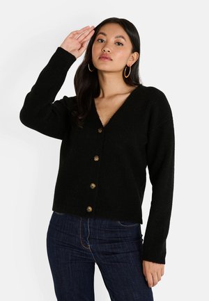Cardigan en tricot noir avec un col en V, doté de boutons en bronze et de manches longues. Le tissu semble doux avec une finition légèrement texturée.