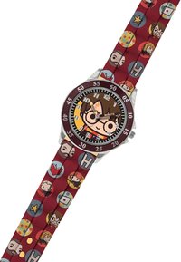 Kleurrijke horloge met een ronde bruine wijzerplaat, speelse karaktergrafieken en een rode band met cirkelvormige iconen en speelse patronen.