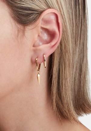 Goldene Creolen mit einem hängenden, spitzen Charm. Das Design zeichnet sich durch eine polierte Oberfläche und eine geometrische Form aus, die eine moderne Ästhetik zur Schau stellt.