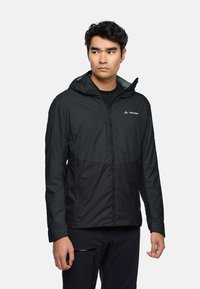 Veste extérieure noire avec une fermeture éclair sur le devant, capuche ajustable et doublure grise contrastante. Fabriquée en matériau léger et résistant  à l'eau.