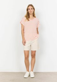 Lett, kortærmet top med pink og hvide horisontale striber, V-udskæring, parret med beige shorts og hvide sneakers. Simpelt design.