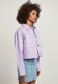 Lavendelcroppad denimjacka med två framfickor, knappstängning och klassisk krage, tillsammans med en ljusblå denimkjol.