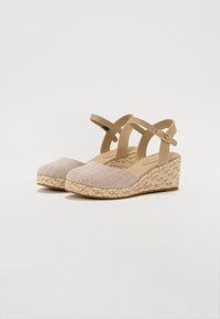 Beige kile sandaler med overdel i stof, tekstureret tåhætte og justerbare ankelstropper. Jute-indpakket mellemsål giver et naturligt look.