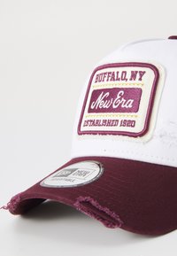 Verstellbare Kappe mit weißer Krone und kastanienbraunem Schirm. Ausgestattet mit einem gestickten Patch mit "New Era" und "Buffalo, NY", sowie abgetragenen Akzenten.